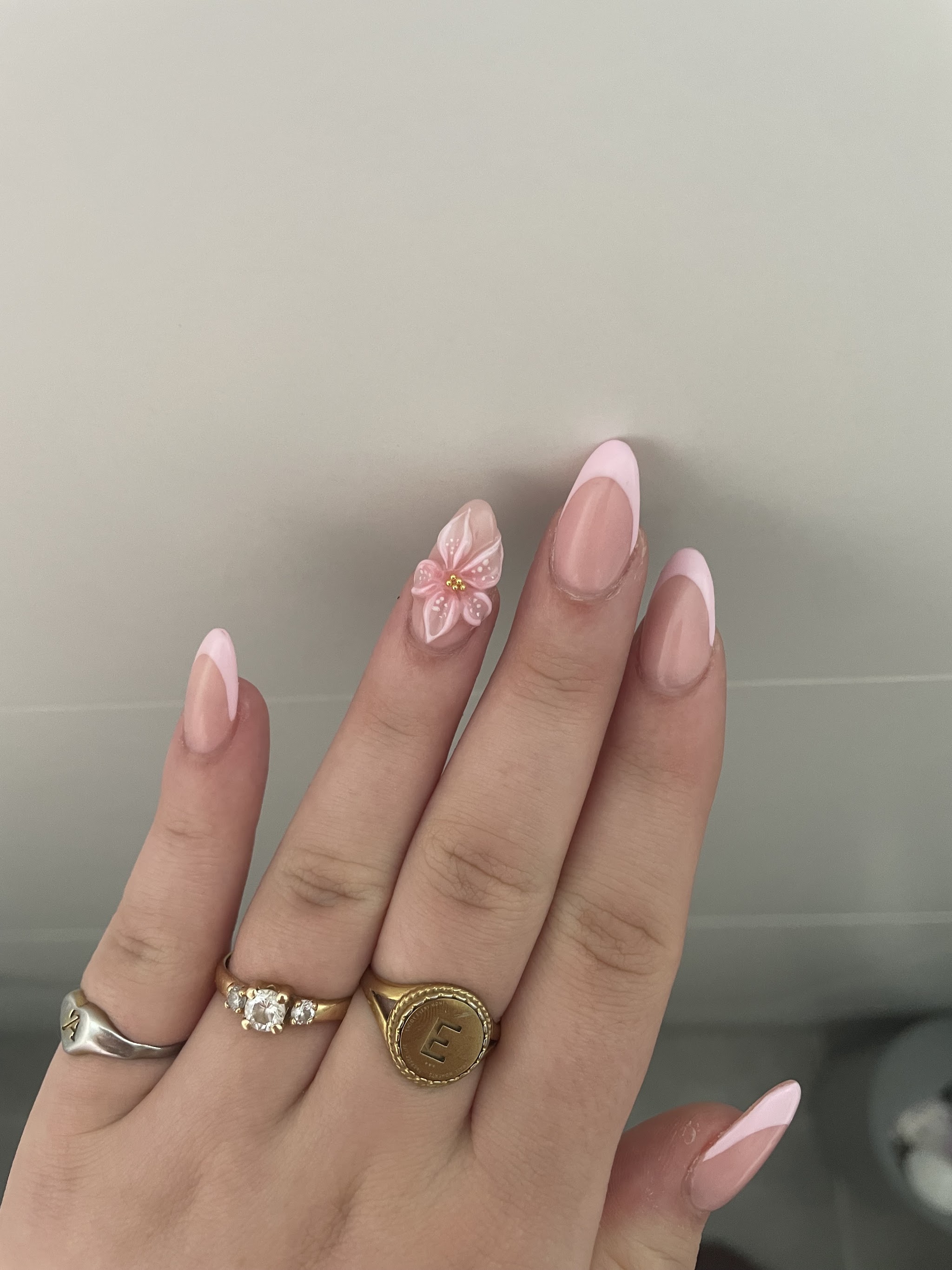 Zachtroze manicure met een bloem op de ringvinger